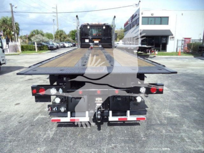 Kenworth T880 rollback truck bed seen from rear showing flatbed with ramps and tow hitch components.