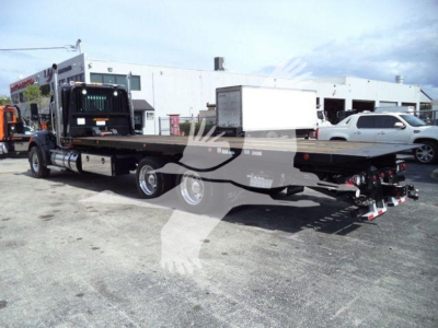 Kenworth T880 rollback truck chassis with flatbed and rear towing equipment, side view showing extended bed and dual rear axles.