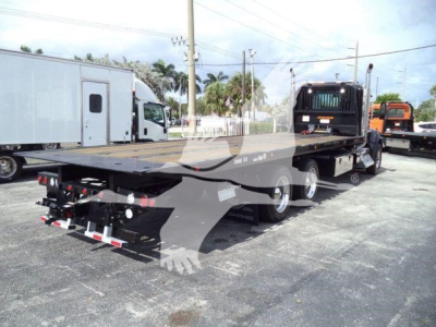 Kenworth T880 rollback truck rear view showing flatbed and triple-axle configuration.