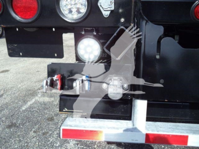 Truck rear with battery disconnect and bumper hitch on Kenworth T880 rollback truck; round tail light, LED work light, and chrome bumper visible.