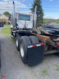 Truck rear view of a used 1999 Mack CH613 semi tractor with dual rear axles, tall exhaust stacks, and air lines; mud flaps installed and fifth wheel scuffed undercarriage.