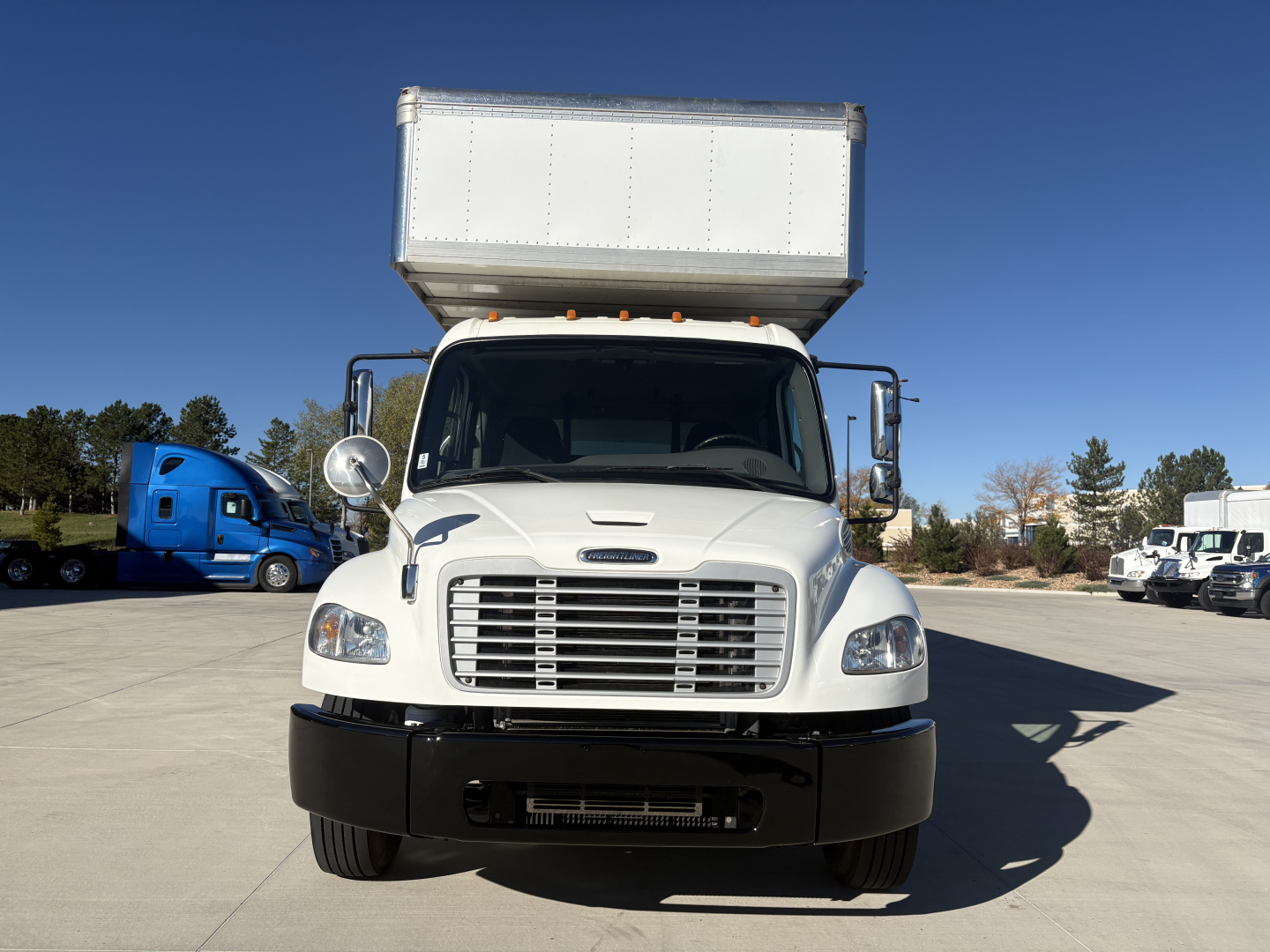 Front view of a 2019 Freightliner M2-106 box truck with a raised cargo box, chrome grille, large side mirrors, and white cab.