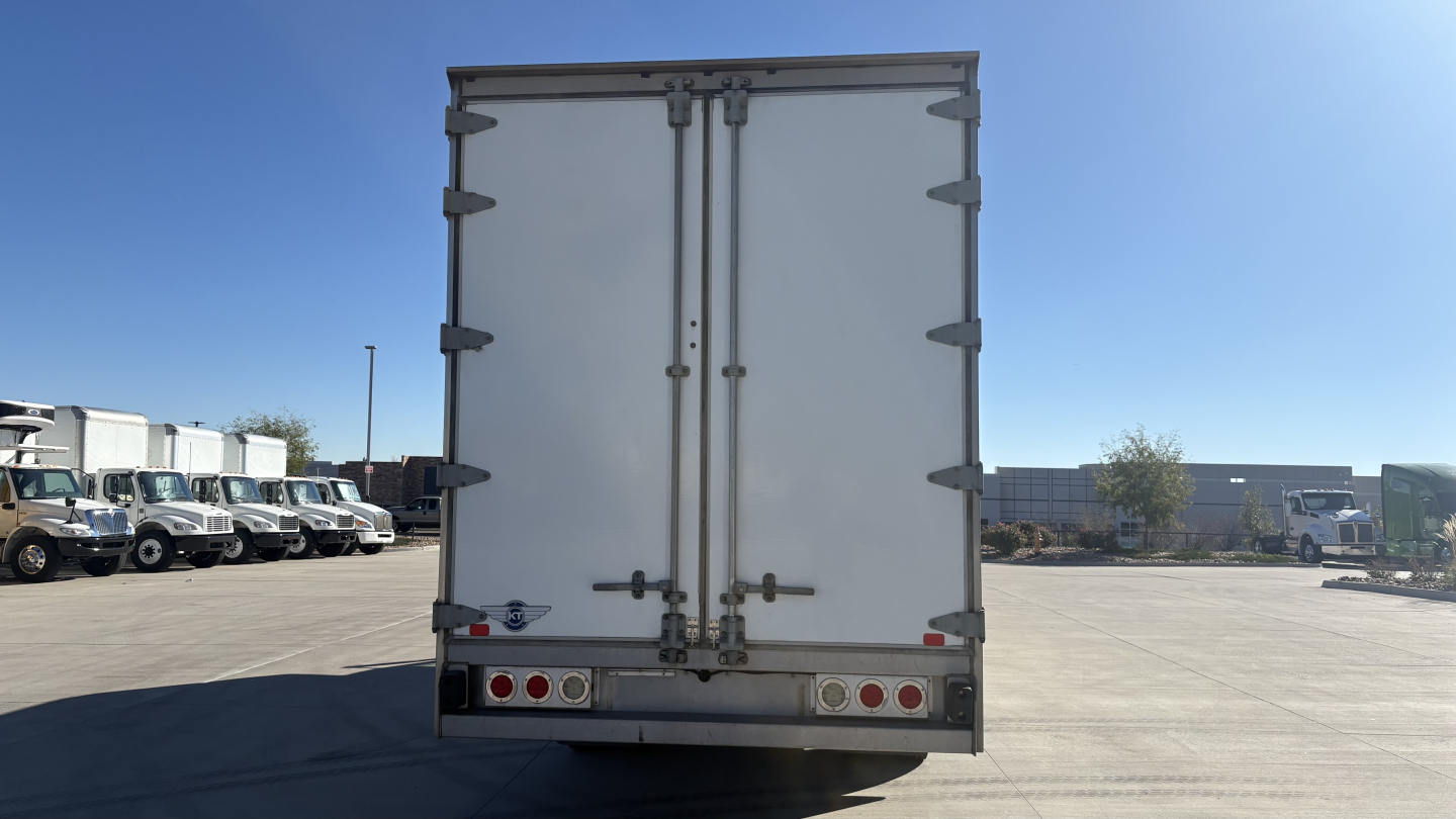 Freightliner M2-106 rear view with closed cargo doors and taillight assemblies in a truck yard.