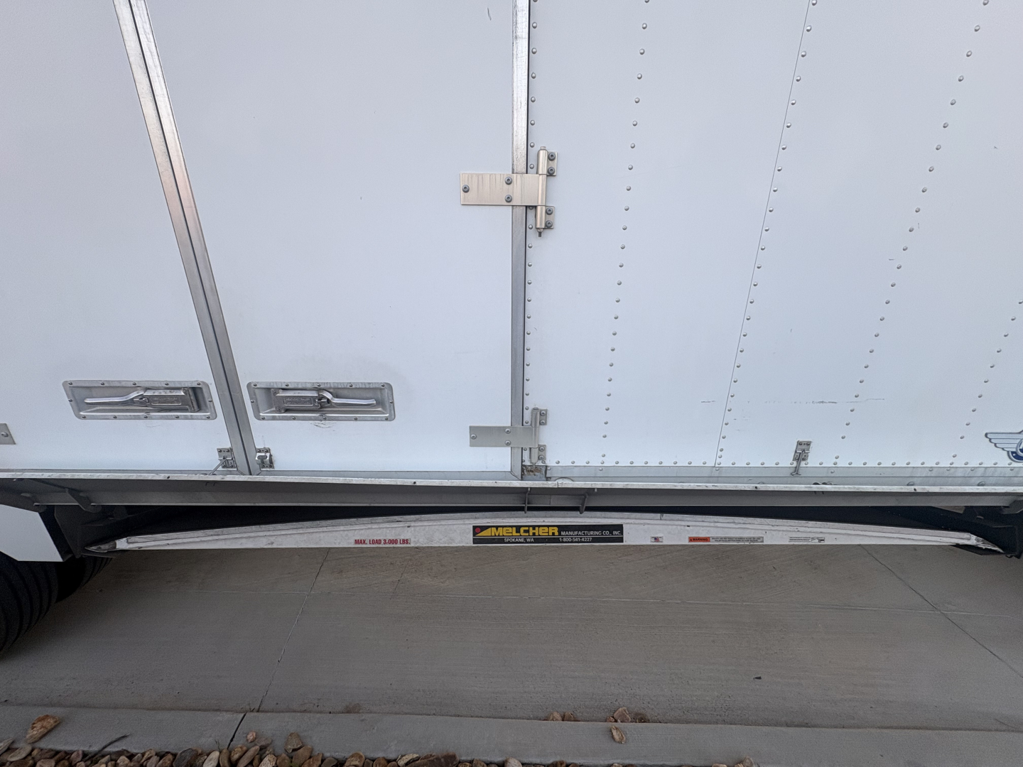 Freightliner M2-106 side view showing side drop door and undercarriage steps with a small label on the sill.