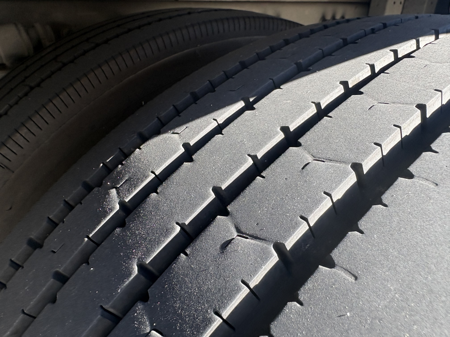 Truck tire tread close-up on Freightliner M2-106 listing showing tire grooves and sidewall portion.