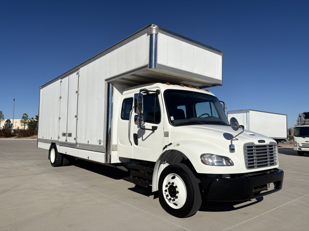 Freightliner M2-106 box truck in white with cab over engine and a large box body, front view showing grille, headlights, and side mirrors.