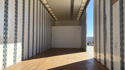 Freightliner M2-106 box truck interior cargo area with metal wall rails and wooden floor, empty loading space.