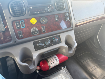 Truck dash area showing woodgrain panel with switches, gauges, and a red fire extinguisher mounted under the center console.