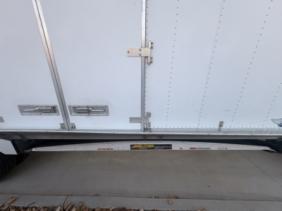Freightliner M2-106 side view showing side drop door and undercarriage steps with a small label on the sill.