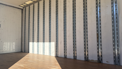 Trailer interior cargo area of a 2019 Freightliner M2-106 box truck showing metal wall framing and wooden floor.