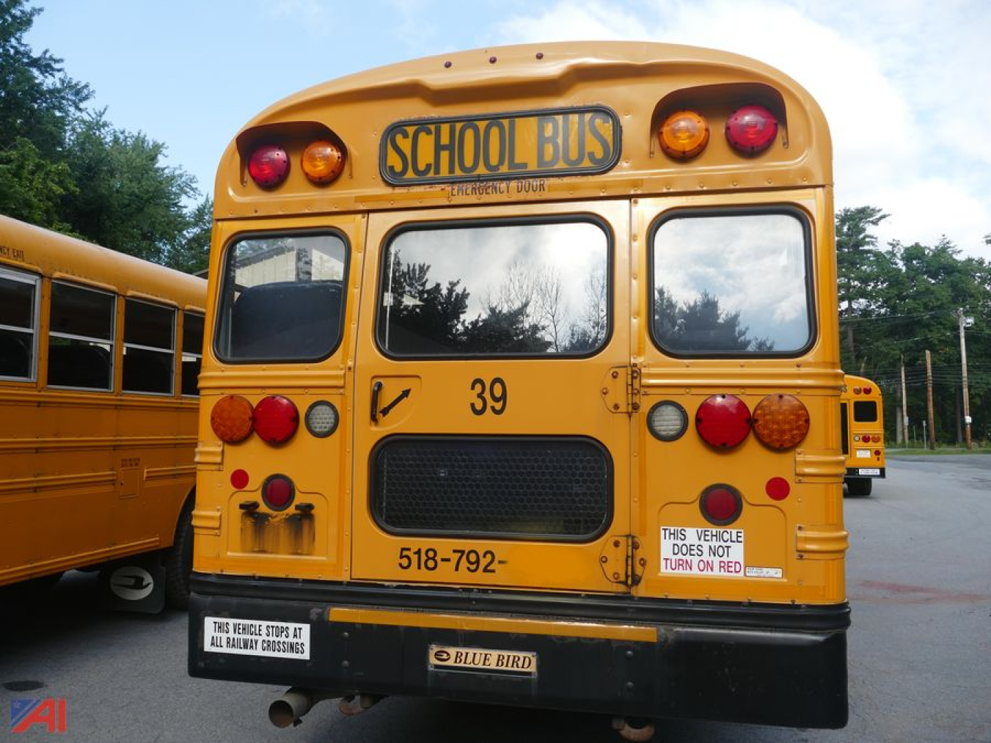 Rear view of a yellow 2016 Blue Bird Vision school bus with 'SCHOOL BUS' sign, rear lights, license-like numbers 39 and 518-792, and a bumper sticker.