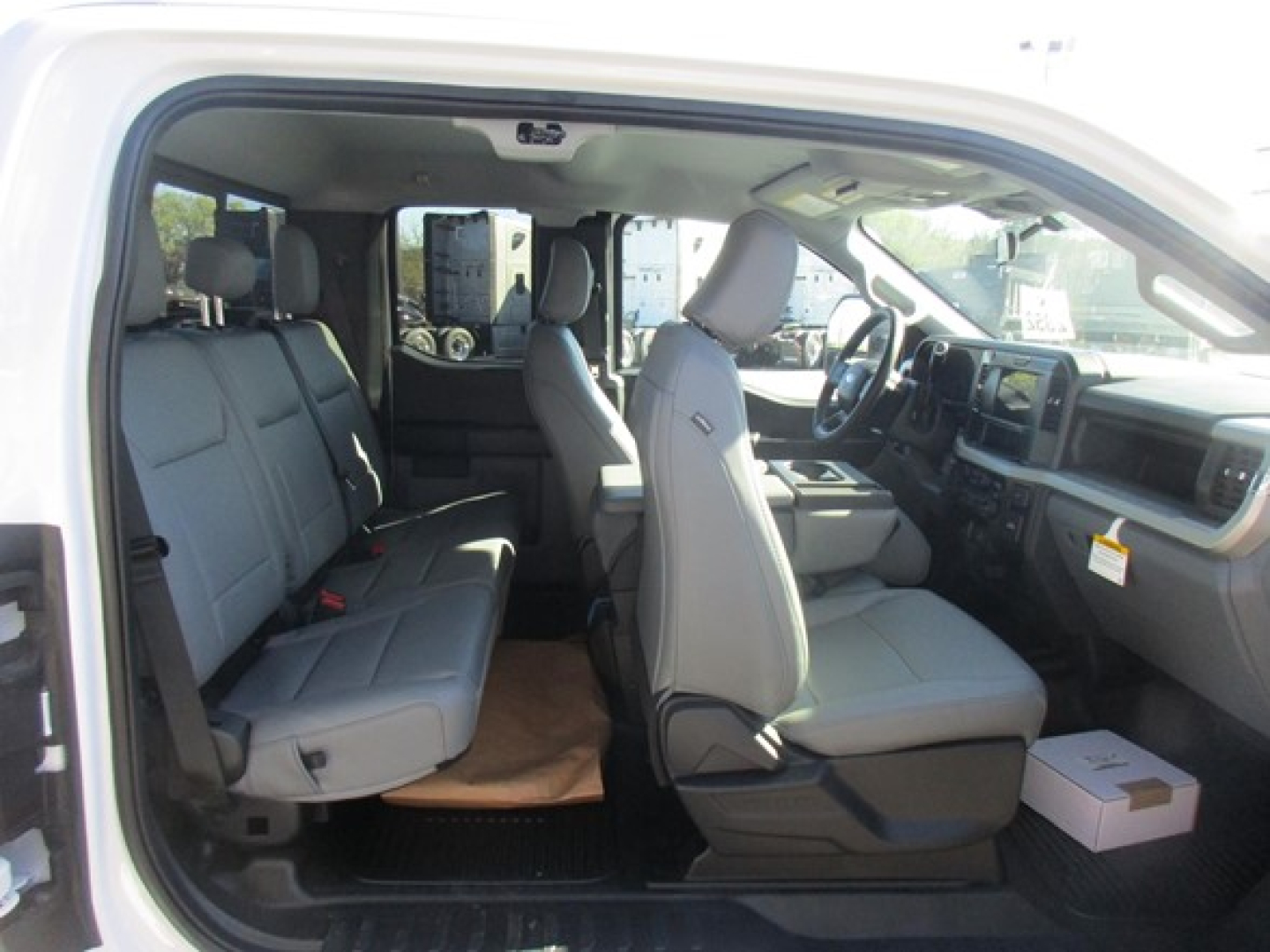 Ford F-350 cab and chassis interior showing front bucket seats and rear bench seating, light gray upholstery, dashboard and steering wheel visible.