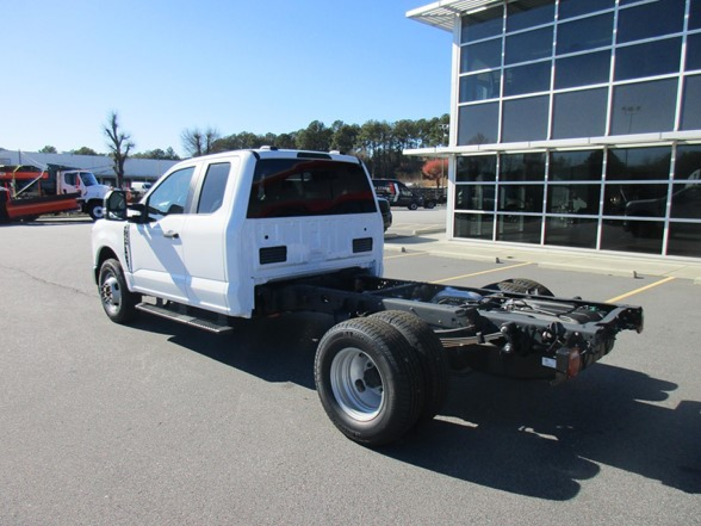 Truck cab and chassis rear three-quarter view showing chassis frame and rear wheels with white cab, no bed installed, dealership lot.