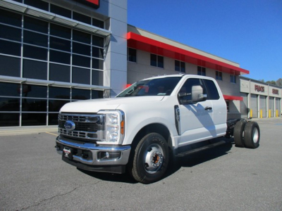 Ford F-350 cab and chassis truck in white, front three-quarter view, with exposed rear chassis and wheel drums, dealership lot in background.