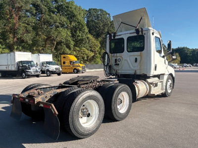 Freightliner Cascadia126 tractor rear 3-axle chassis visible with sleeper cab, white paint, dump-style fuel tank, and raised hood.