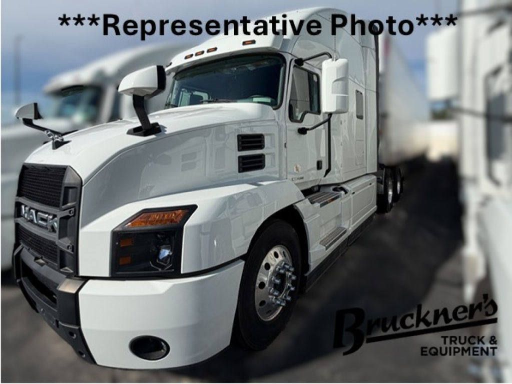 Conventional sleeper truck in showroom photo showing front three-quarter view of a white 2023 Mack AN64T70 with Buckner's watermark.