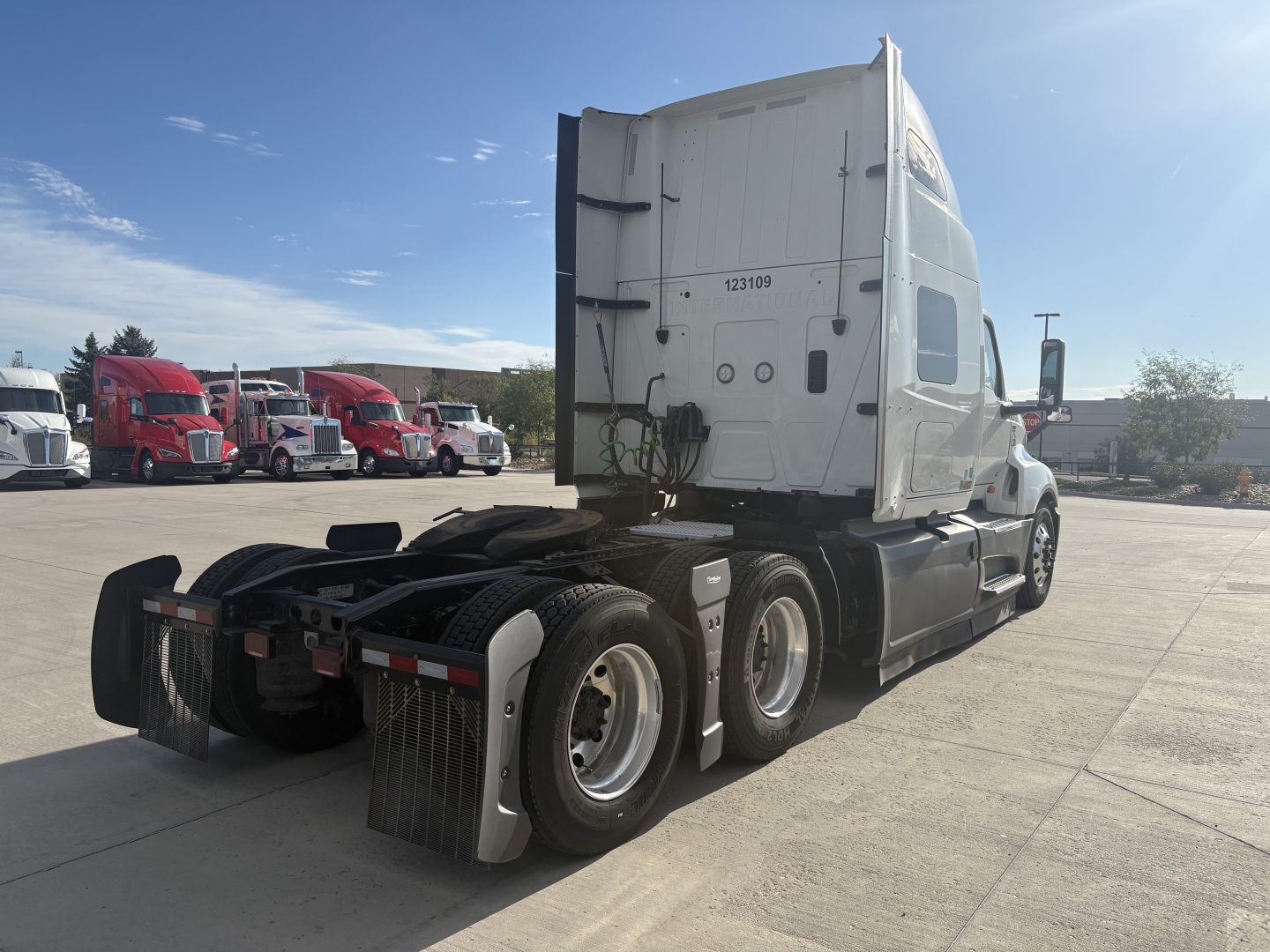 Truck: 2023 International LT625 conventional sleeper tractor, rear three-quarter view showing chassis, tandem axles, mud flaps, and white cab. Visible text includes numbers on the cab (1231909) and general truck features; no identifiable li
