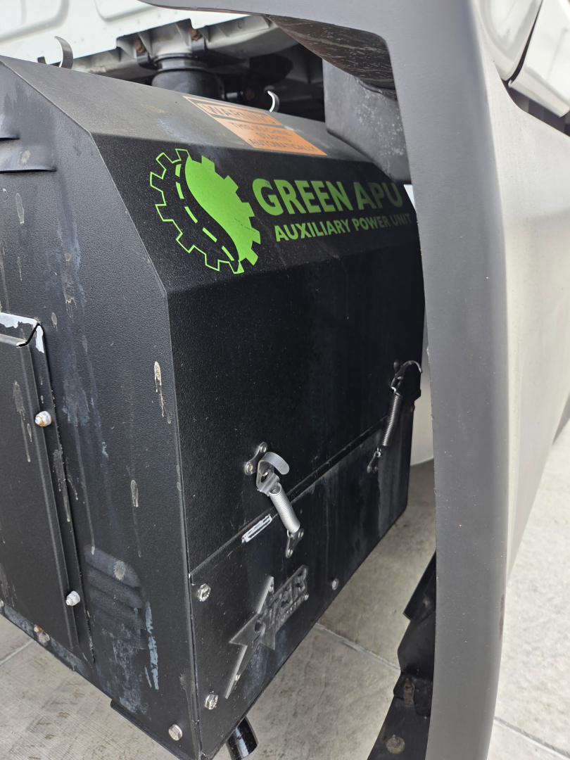 Truck engine bay showing Green Power Aux power unit with handle and latches visible on the side.
