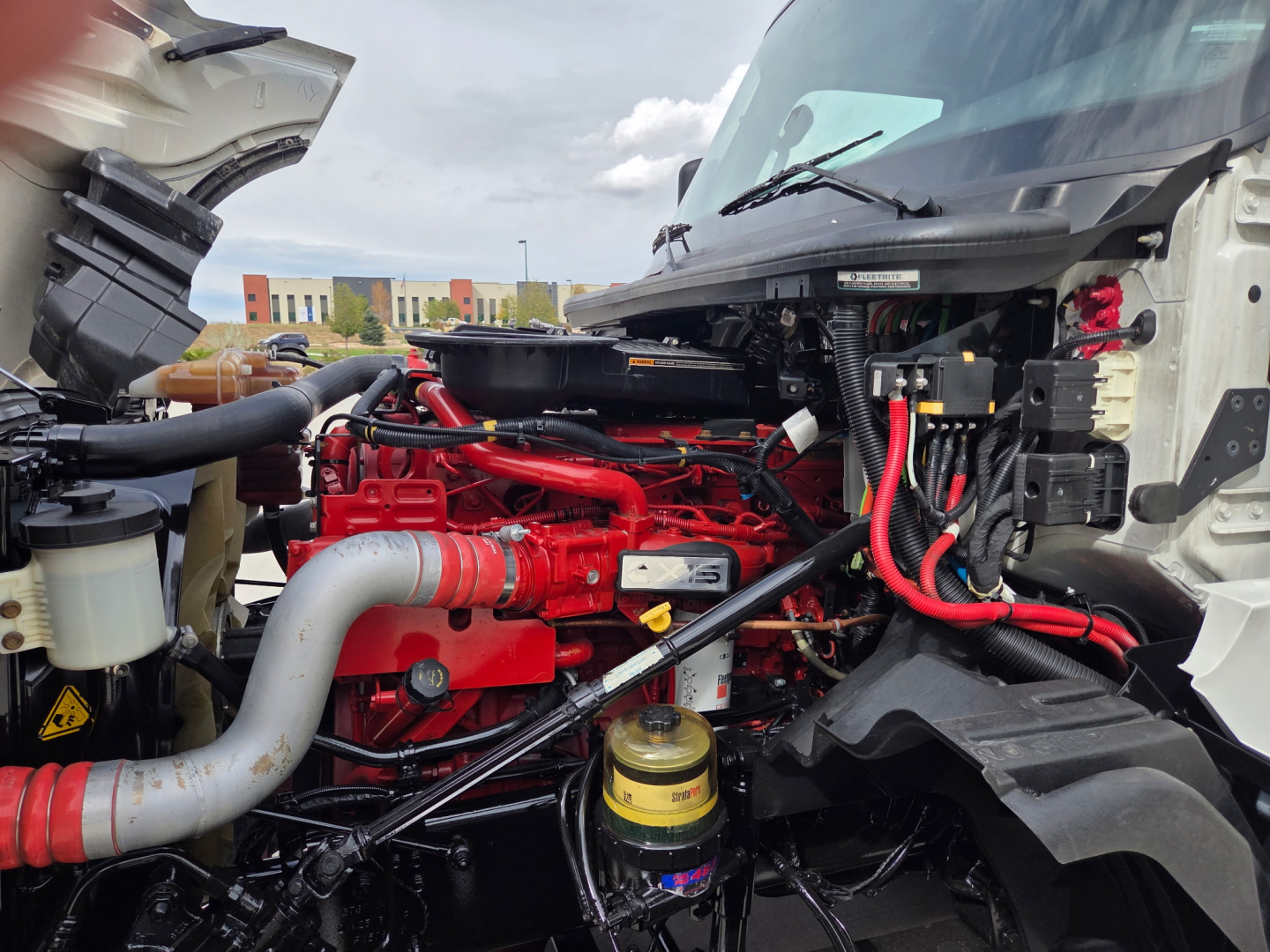 International LT625 engine bay showing red engine components and various hoses and wiring under open hood.