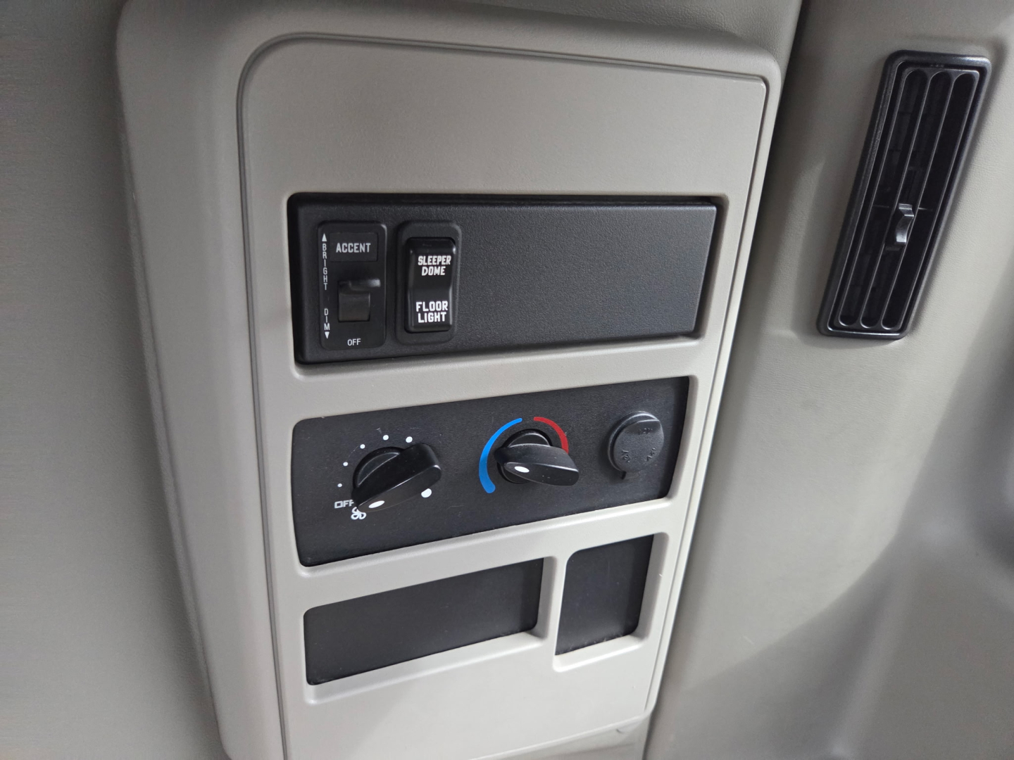 Truck interior dash panel with climate controls and storage compartments visible in center, plus vertical vent to the right.