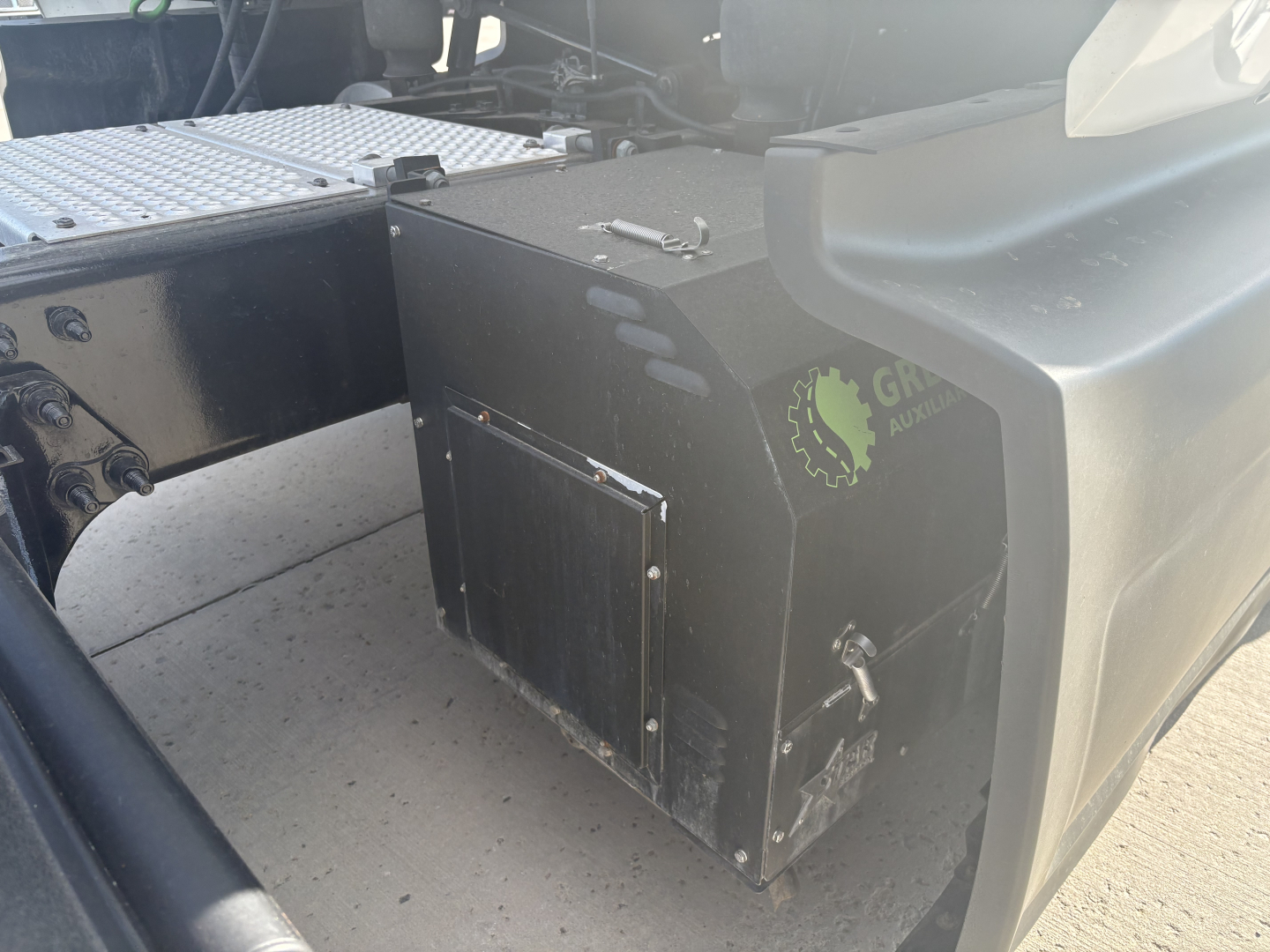 Truck cab area showing a black rectangular fuel or storage box with metal latch, mounted next to chassis on a 2023 International LT625 truck.