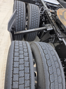 Dual rear axles showing treaded truck tires and suspension components in an International LT625.