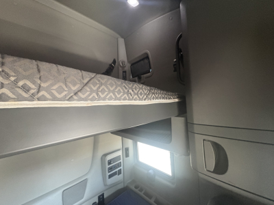 Interior sleeper cab area of a 2023 International LT625 truck with bunk bed and small window visible.