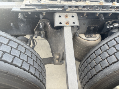 Truck chassis showing dual rear axle and suspension components in the undercarriage of a 2023 International LT625. Visible are tandem axle frame crossmember, leaf springs, air bag/air suspension lines, and dual tires.