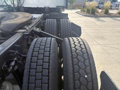 Tractor-trailer chassis showing dual rear axles with dual tires and suspension components in view.