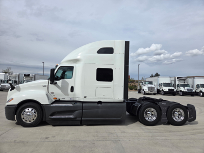 Truck side profile showing a white 2023 International LT625 tractor with sleeper, chrome wheels, and fuel tanks visible.