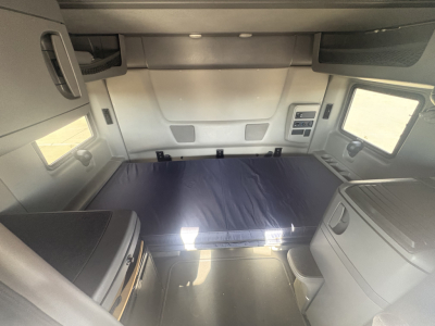 Truck sleeper cab interior with bed platform and side windows.