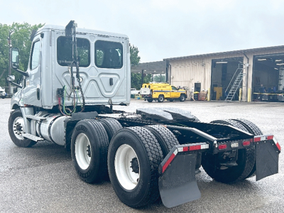 Freightliner Cascadia126 tractor tractor rear view showing dual rear axles and fifth wheel, with mud flaps and license plate area, silver cab and black chassis.