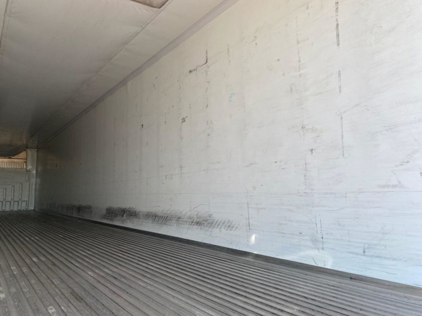 Trailer interior wall and floor of a 2020 Wabash refrigerated trailer showing cleaned metal with horizontal ribbing on the floor and light scuffs along the side wall.