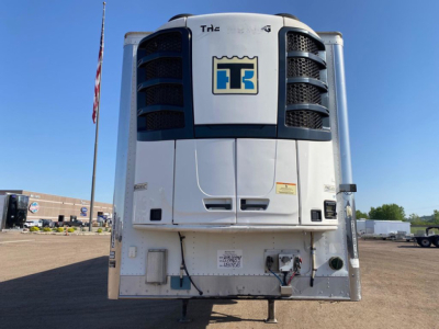 Wabash refrigerated trailer front view showing TH2 logo, cooling unit, and access doors with ladder, in a truck yard.