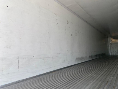 Trailer interior showing ribbed metal floor and white sidewalls with scuffs; empty refrigerated trailer cargo area interior.