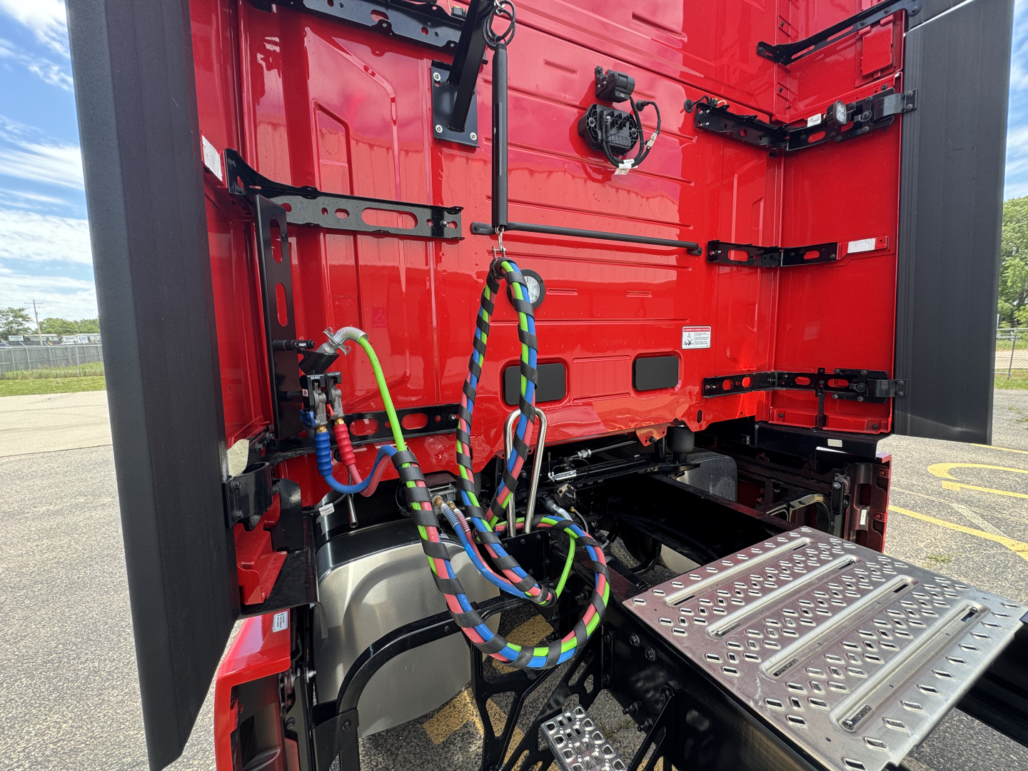 Mack PR64T76H truck cab interior showing colorful braided air lines and metal step plate in the cab access area.