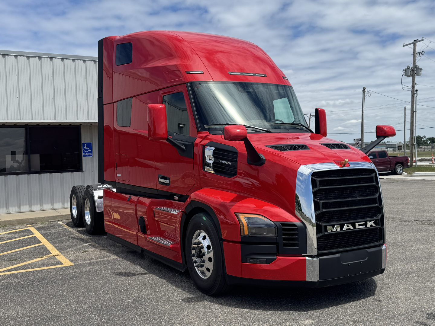 Mack PR64T76H conventional sleeper truck in red, front three-quarter view, showing large grille, side mirrors, and dual rear axles.