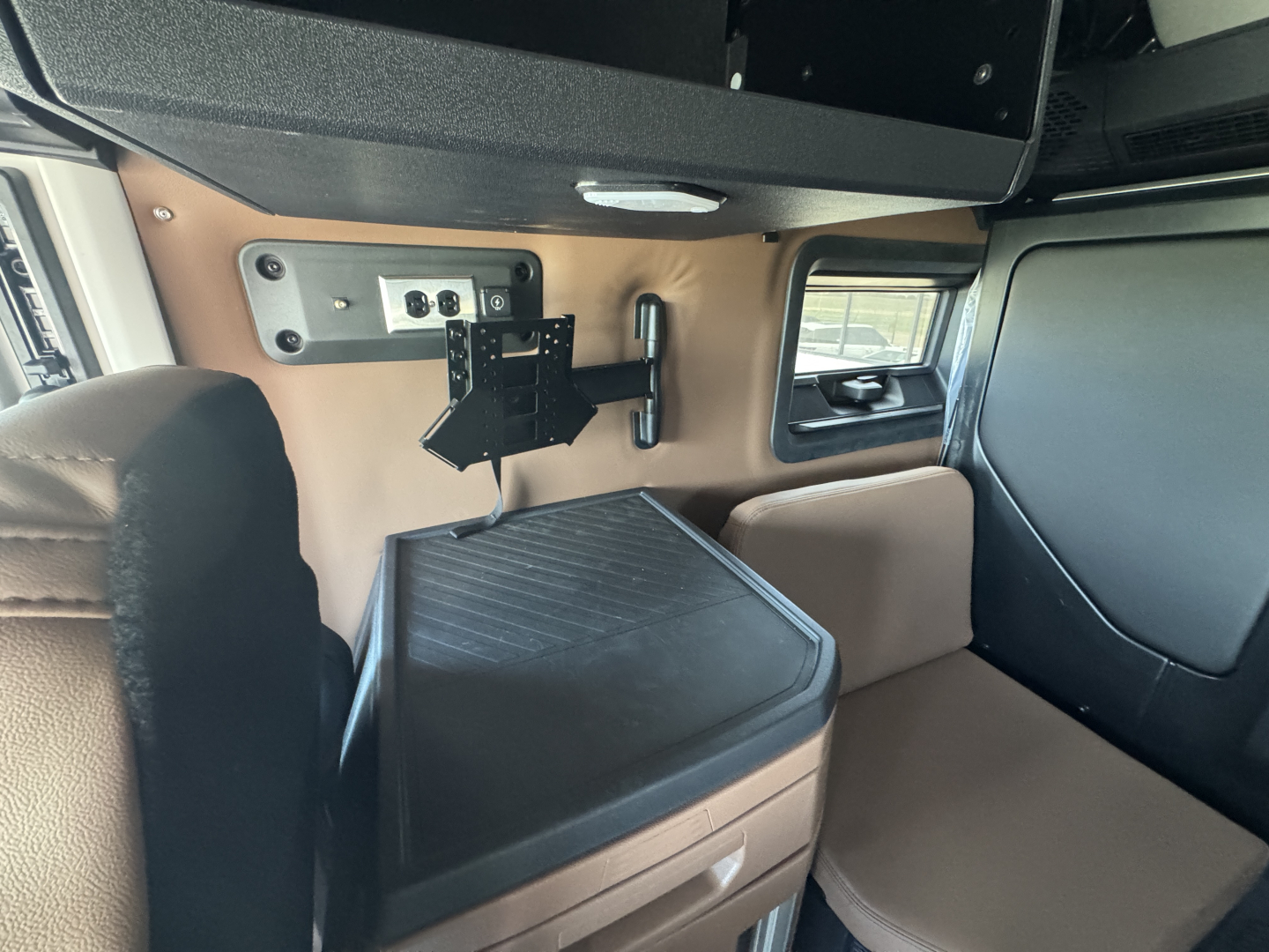 Interior of new Mack PR64T76H showing sleeper cab area with mounting bracket and control panel, brown wall panel, and black storage bin.