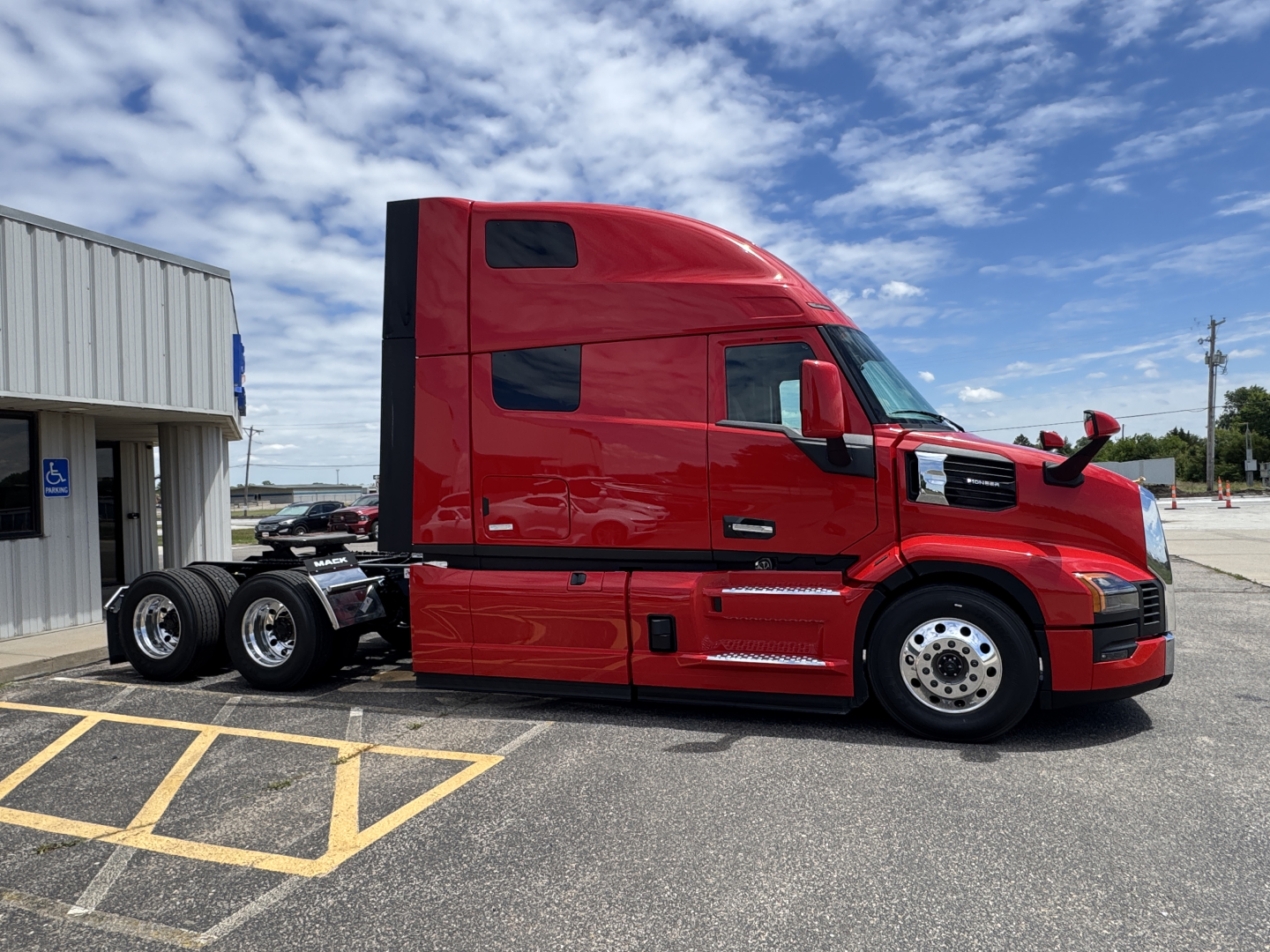 Mack PR64T76H heavy-duty tractor in red side profile view showing cab with sleeper, windows, mirrors, and dual rear axles.