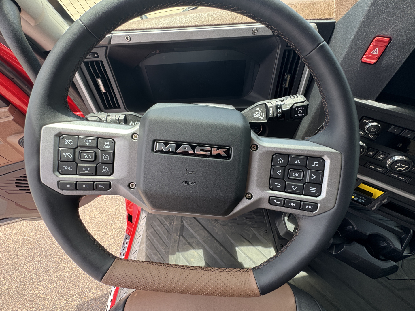 Mack steering wheel with many control buttons in a new Mack PR64T76H truck cab; dashboard and controls visible.