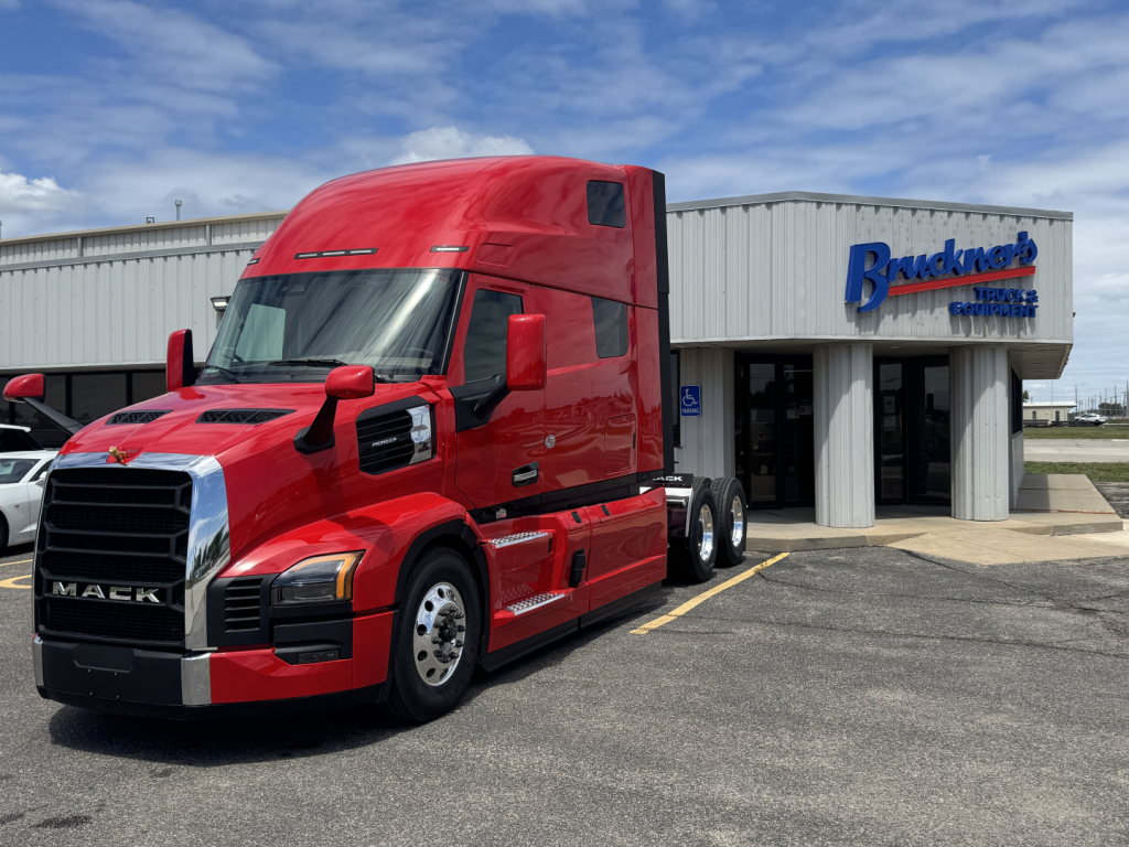 Mack PR64T76H truck in front of a dealership building.