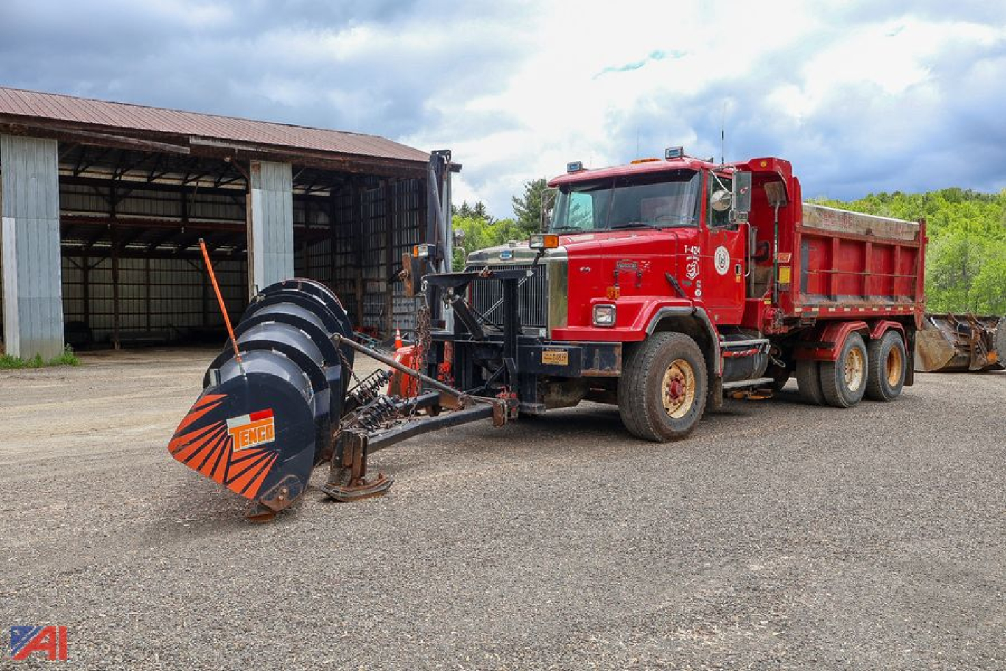Volvo Autocar 6x4 dump truck with plow attachment in a yard, red cab, large black plow winch and orange tip blades.