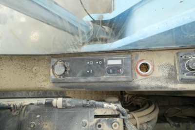 Control panel showing switches and circular dials on a blue Terex MHL340D loader arm area; visible wires and dusty machinery components.