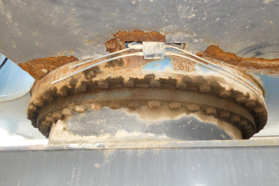 Circular gear and rusted mounting surface with heavy, toothed ring gear and bolted flange.