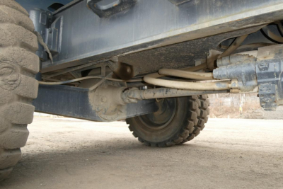 Wheel and suspension undercarriage of a Terex MHL340D boom lift showing axles, steering linkages, and hydraulic lines.