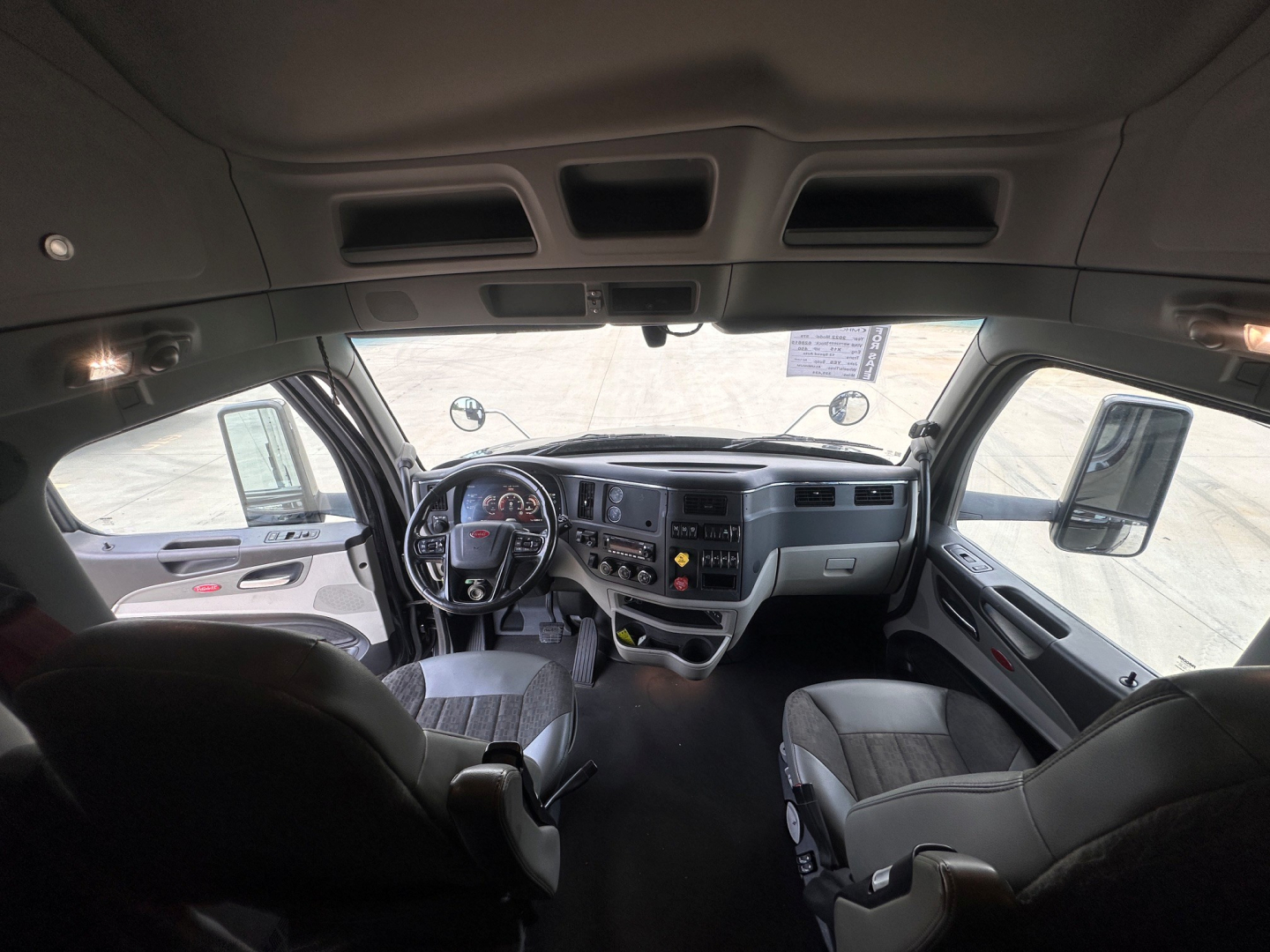 Peterbilt 579 truck interior cab view from driver seat showing dashboard, steering wheel, and front seats in a sleeper cab.