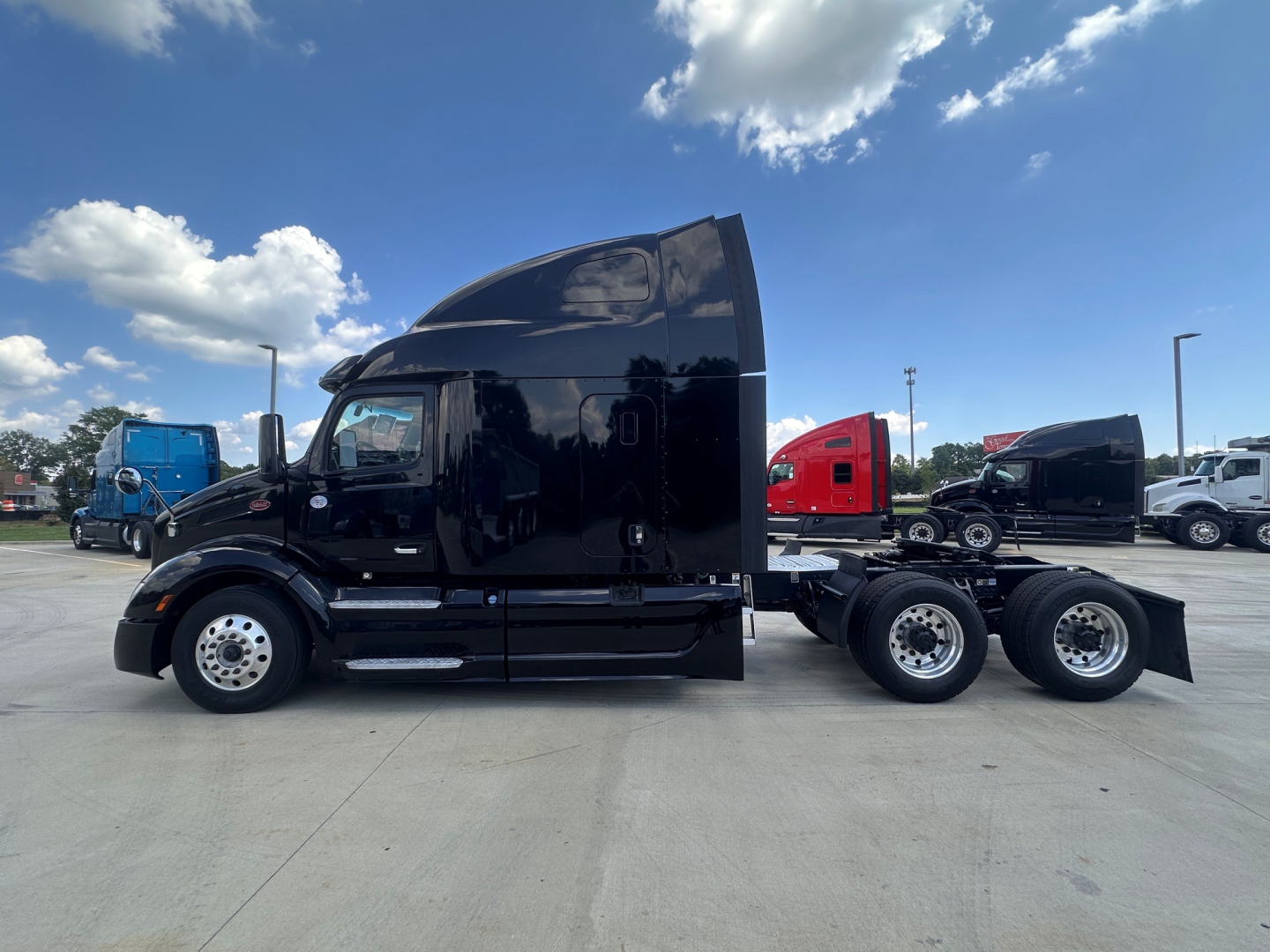 Peterbilt 579 tractor with a black exterior, side view showing sleeper cab, two-axle with a tandem rear, and chrome fuel tanks.