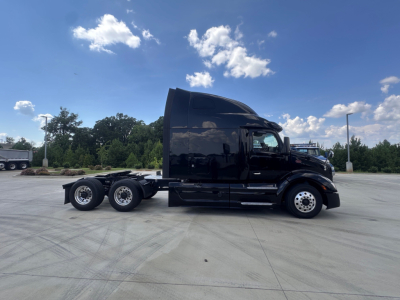 Peterbilt 579 tractor in a parking lot, side view showing the sleeper cab, black paint, 6x4 configuration with dual rear axles, no visible logos or text.