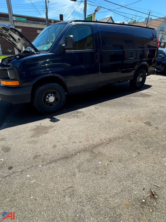Rear-side view of a dark blue 2008 Chevrolet Express full-size passenger van with front hood open, showing side doors and wheel wells.