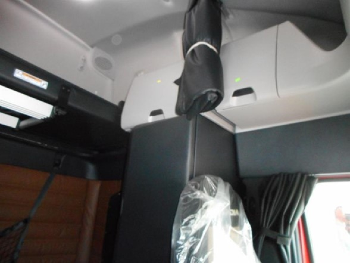 Freightliner Cascadia truck interior view showing sleeper cab with overhead storage and window shade.